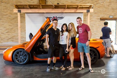 group of people smiling in front of a luxury car at veloce vault