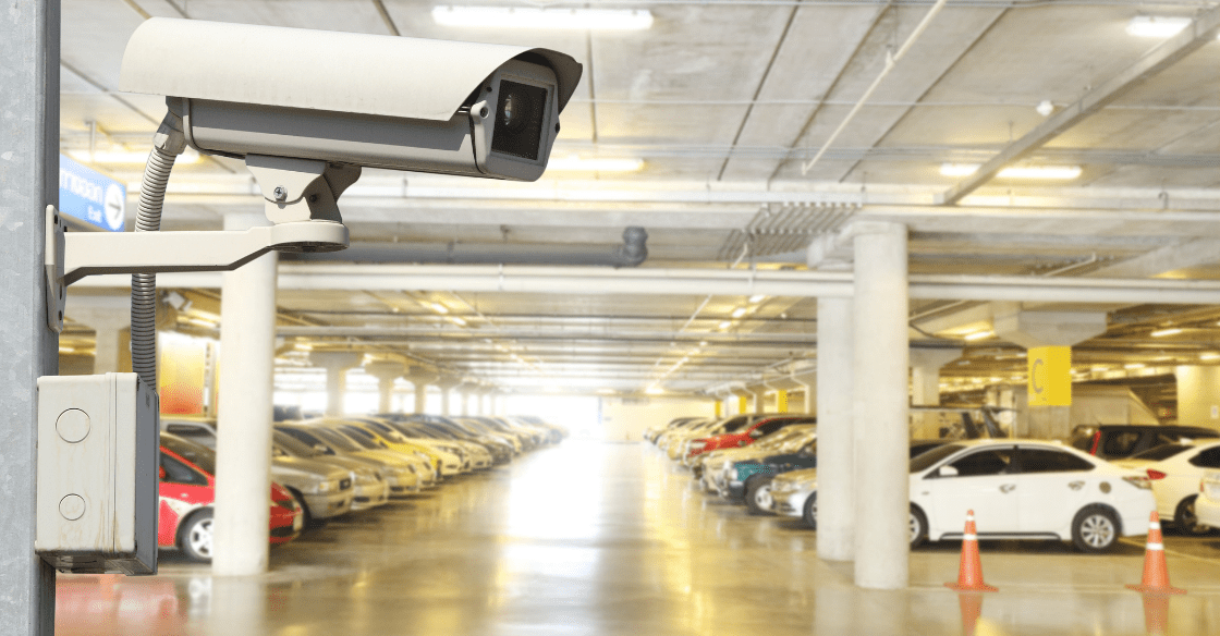 A CCTV camera monitors cars parking in a professional car storage facility.